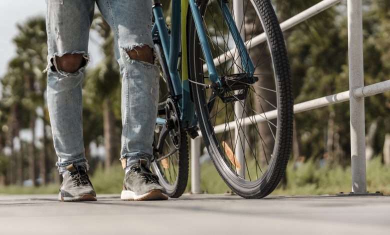 Homem caminhando ao lado de sua bicicleta