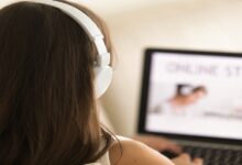 Pessoa com fones brancos usando notebook para estudar online