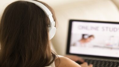 Pessoa com fones brancos usando notebook para estudar online